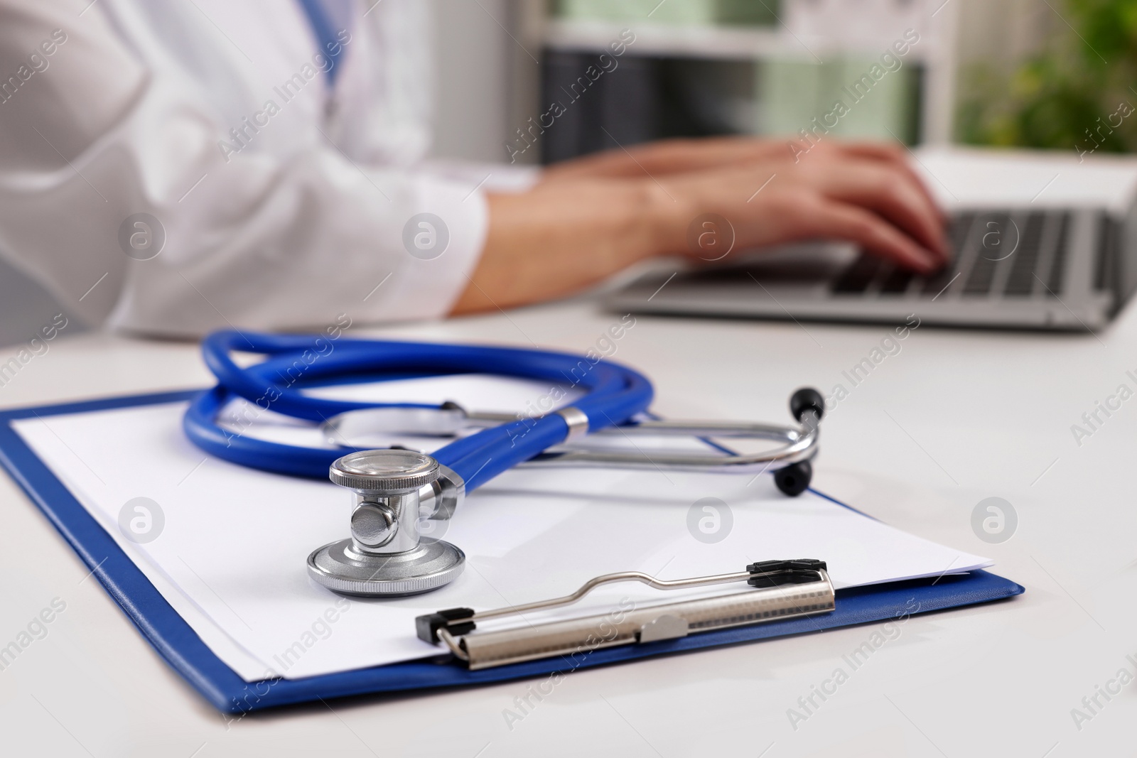 Photo of Doctor during patient consultation, clipboard and stethoscope on white table in clinic, closeup