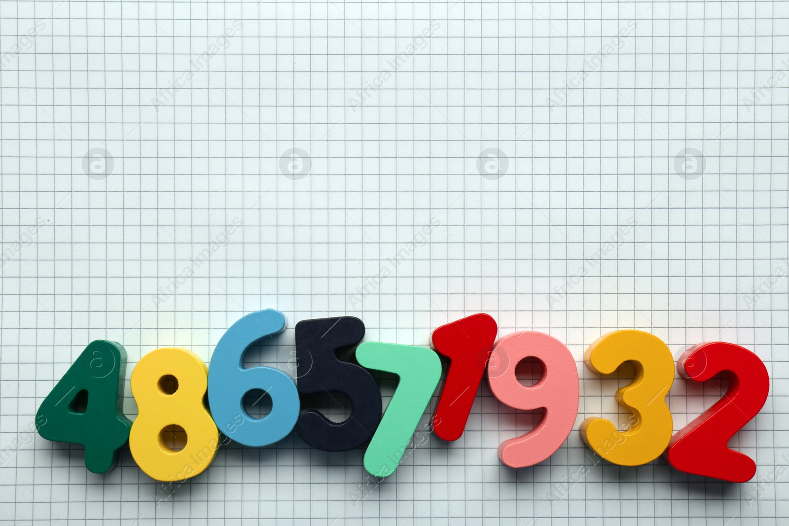 Photo of Colorful numbers on sheet of grid paper, flat lay. Space for text