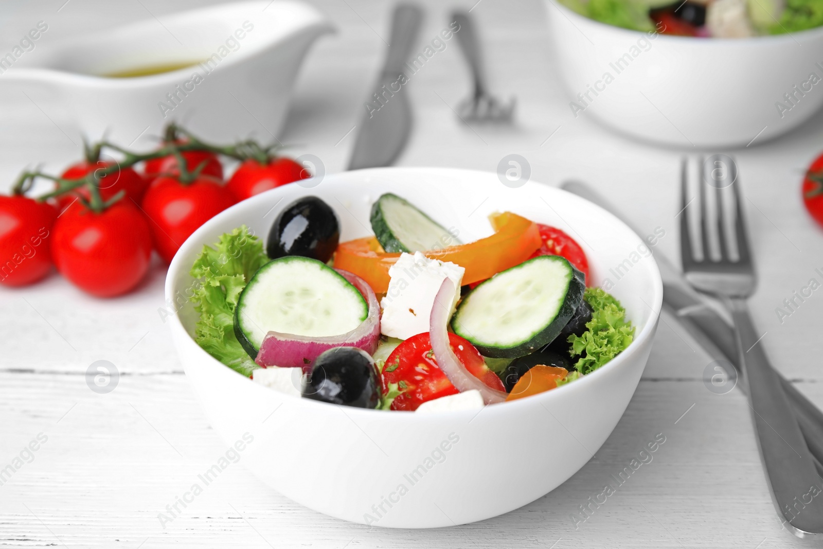 Photo of Tasty fresh Greek salad on white wooden table