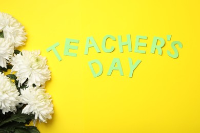 White chrysanthemum flowers and words TEACHER'S DAY on yellow background, flat lay