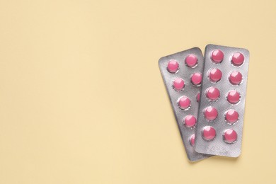 Photo of Pink pills in blisters on beige background, top view. Space for text