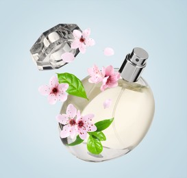 Bottle of perfume and sakura flowers in air on light blue background
