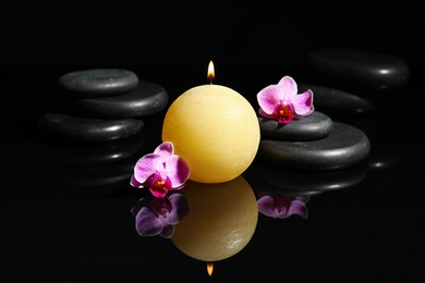 Composition with candle and spa stones on black background