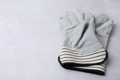 Pair of color gardening gloves on light grey table, closeup. Space for text