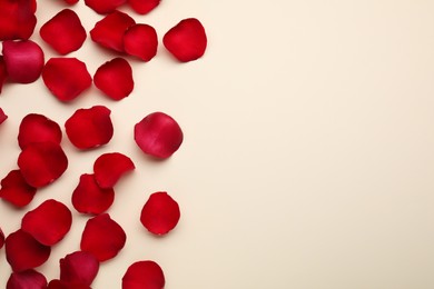 Photo of Red rose petals on beige background, top view. Space for text