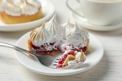 Photo of Tartlet with meringue served on white wooden table, closeup. Delicious dessert