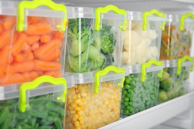 Photo of Containers with deep frozen vegetables in refrigerator