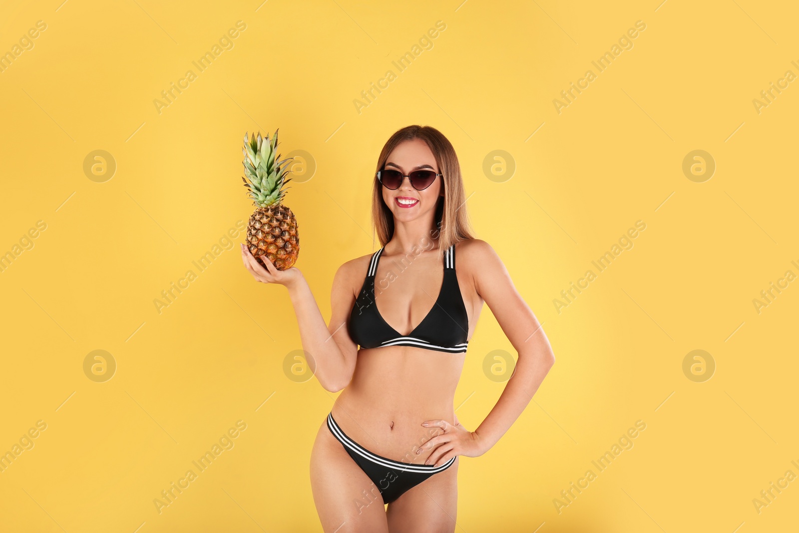 Photo of Pretty sexy woman in stylish bikini with pineapple on color background