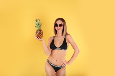 Pretty sexy woman in stylish bikini with pineapple on color background