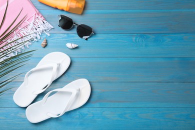 Stylish flip flops and beach objects on light wooden background, flat lay. Space for text