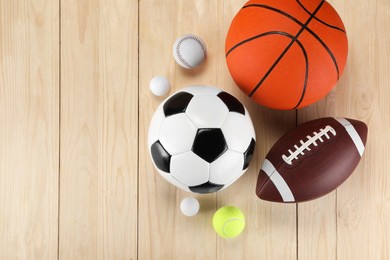 Photo of Many different sports balls on wooden background, flat lay. Space for text