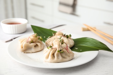 Plate with tasty baozi dumplings on white wooden table