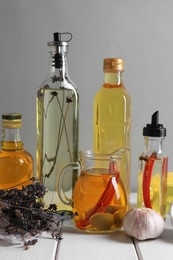 Photo of Different cooking oils and ingredients on white wooden table against grey background