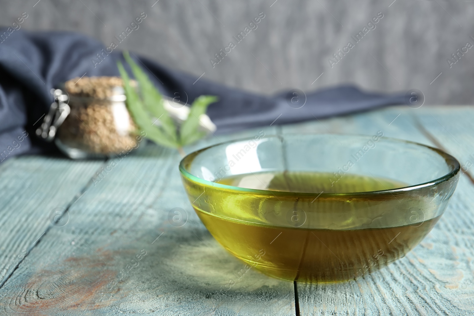 Photo of Glass bowl with hemp oil on wooden table