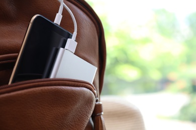 Photo of Charging mobile phone with power bank in backpack, closeup. Space for text