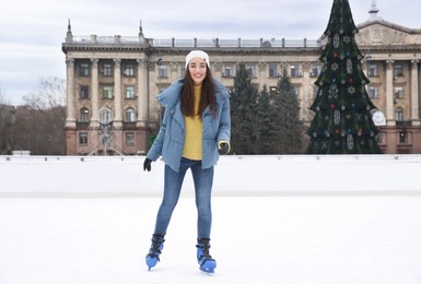 Image of Happy woman skating along ice rink outdoors