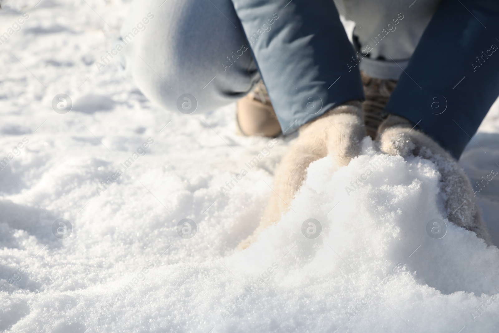 Photo of Woman rolling snowball outdoors on winter day, closeup. Space for text