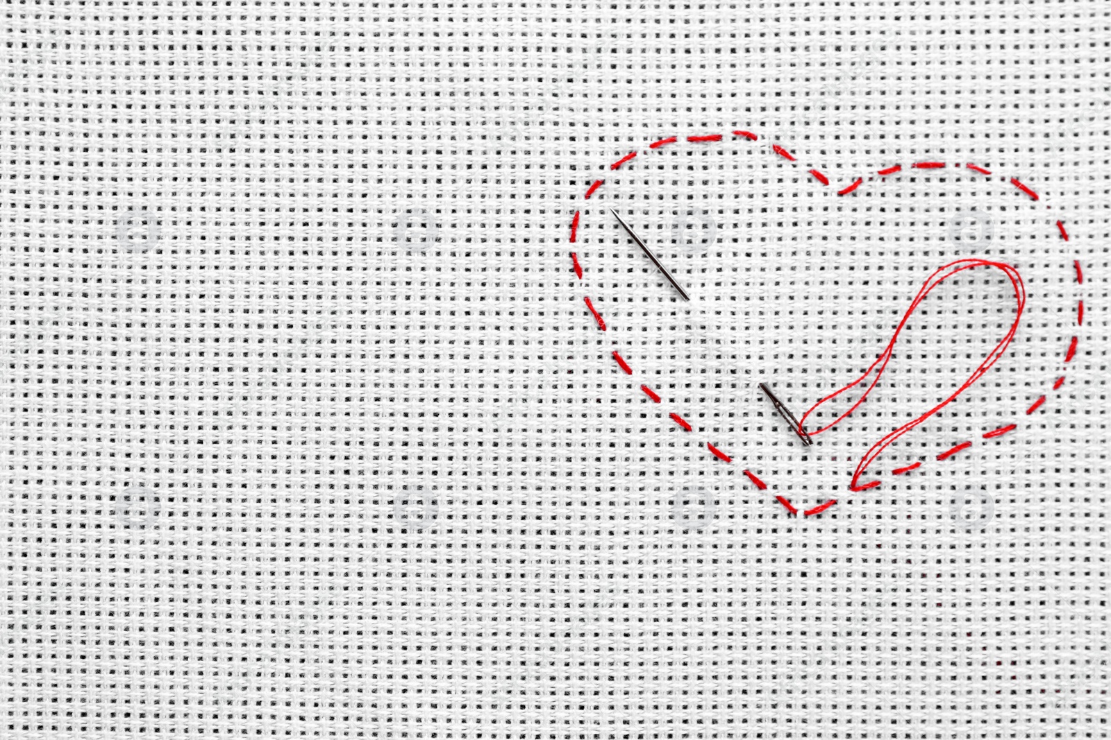 Photo of Canvas with embroidered heart and needle as background, top view. Space for text