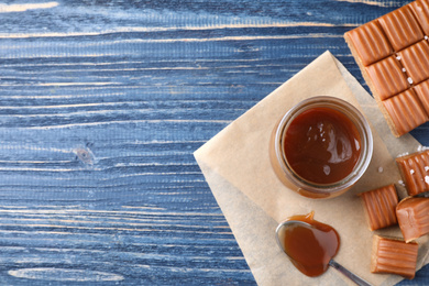 Salted caramel on blue wooden table, flat lay. Space for text