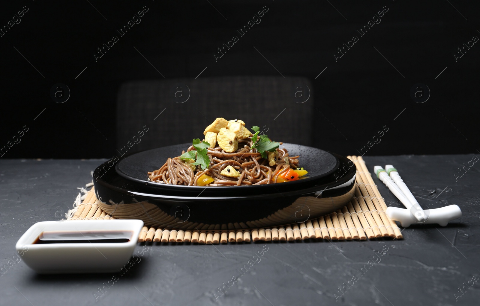 Photo of Stir-fry. Tasty noodles with meat and vegetables served on dark textured table