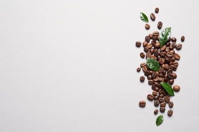 Photo of Fresh green coffee leaves and beans on light background, flat lay. Space for text