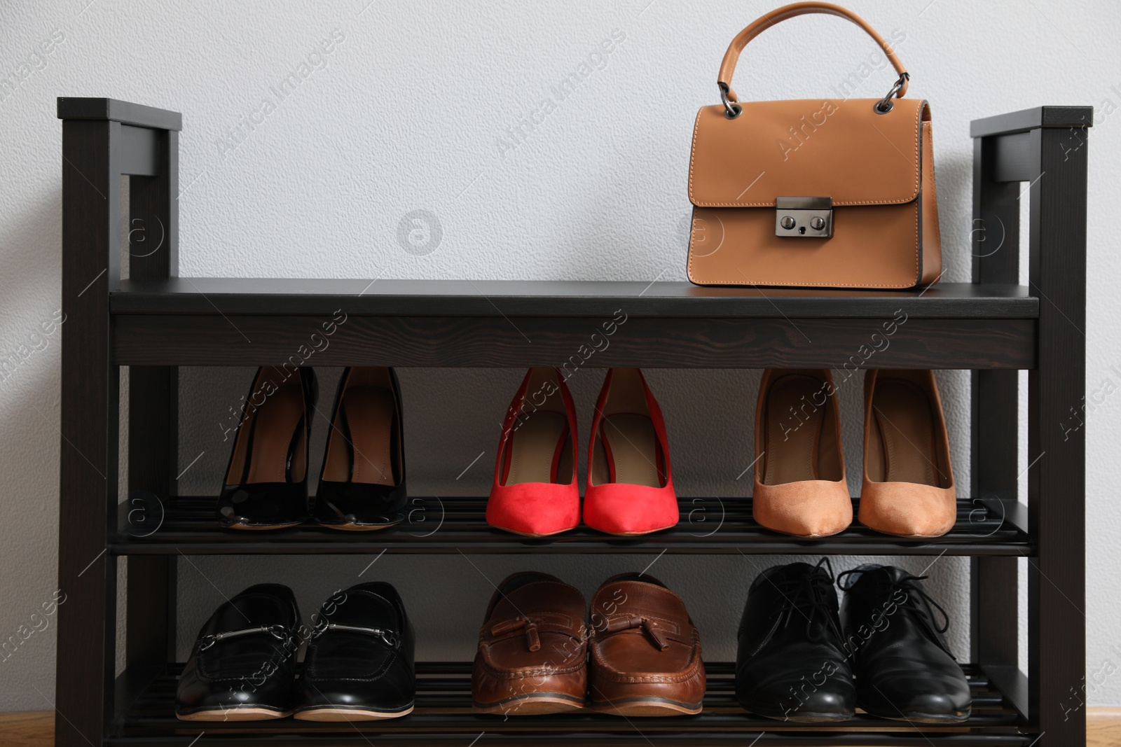 Photo of Shelving unit with shoes and stylish bag near grey wall in hallway