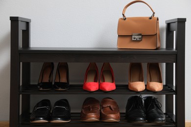 Photo of Shelving unit with shoes and stylish bag near grey wall in hallway