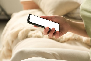 Photo of Woman with smartphone on sofa indoors, closeup