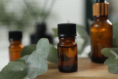 Photo of Aromatherapy. Bottles of essential oil and eucalyptus leaves on table