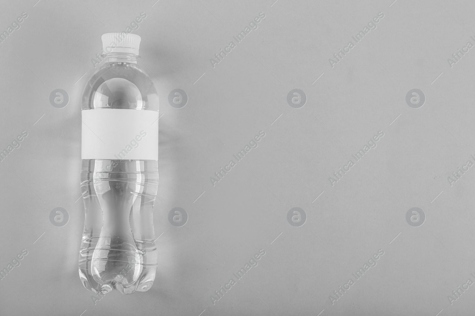 Photo of Bottle of water on light background, top view. Space for text