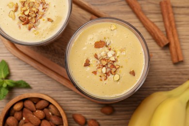 Photo of Tasty banana smoothie with almond and cinnamon on wooden table, flat lay