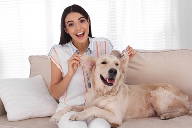 Photo of Young woman and her Golden Retriever dog having fun on couch in living room