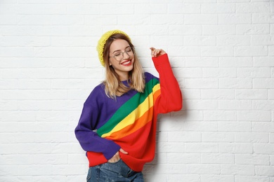 Photo of Beautiful young woman in warm sweater with hat near white brick wall. Space for text