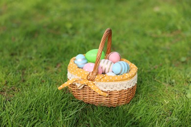 Easter celebration. Painted eggs in wicker basket on green grass