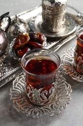 Photo of Tea and date fruits served in vintage tea set on grey table