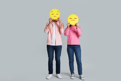 Photo of People covering faces with sad emoticons on grey background