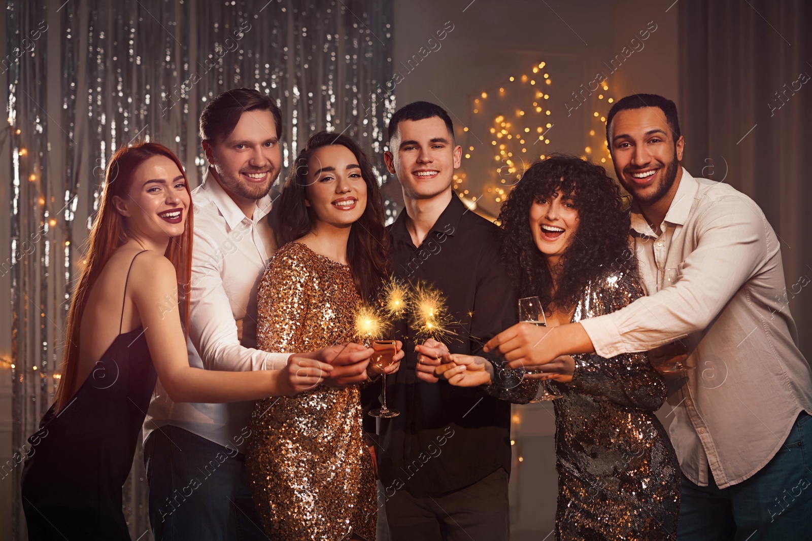 Photo of Happy friends with glasses of wine and sparklers celebrating birthday indoors