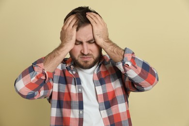 Man suffering from migraine on light green background