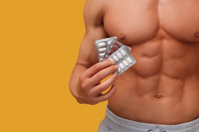 Photo of Weight loss. Athletic man with pills on orange background, closeup. Space for text