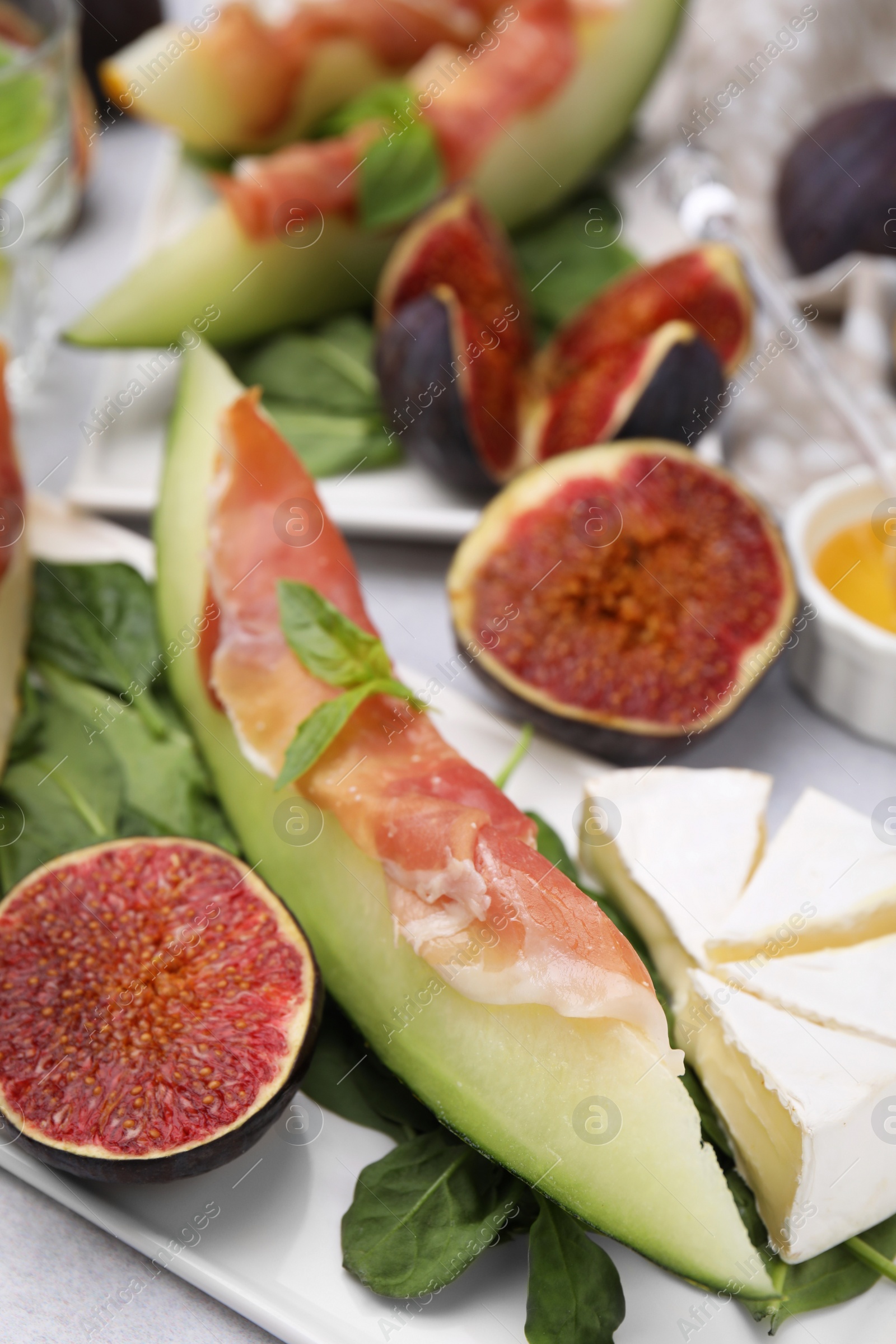 Photo of Tasty melon, jamon and figs served on white plate, closeup