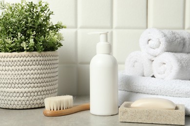 Photo of Different bath accessories and personal care products on gray table near white tiled wall