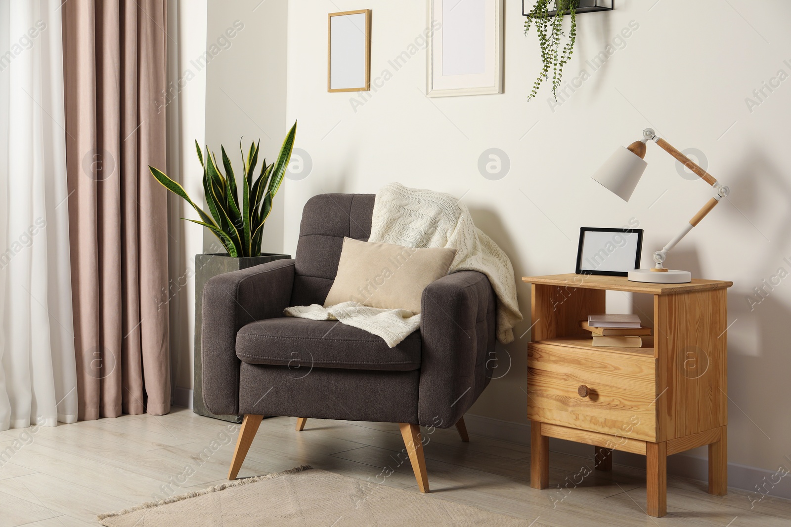 Photo of Cozy room interior with comfortable armchair, desk lamp and beautiful decor elements