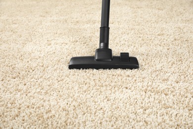 Photo of Removing dirt from beige carpet with modern vacuum cleaner
