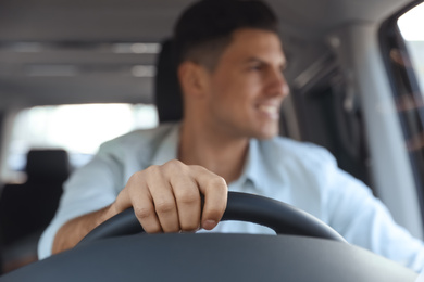 Photo of Handsome man driving his modern car, focus on hand