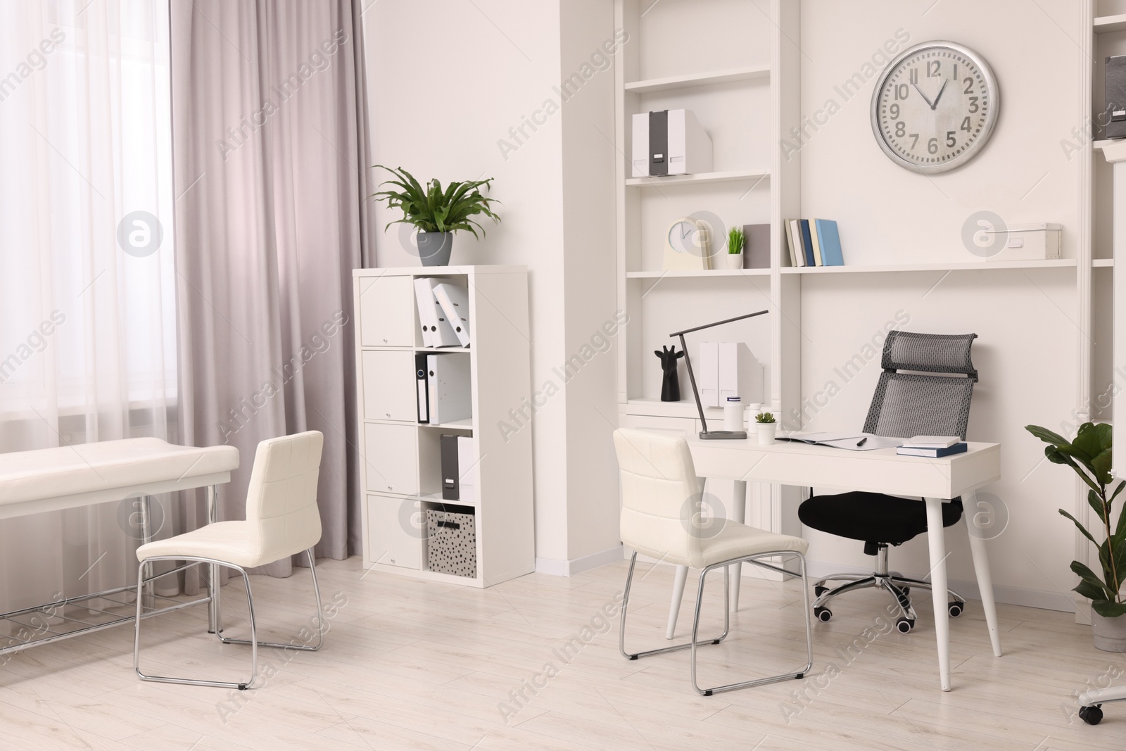 Photo of Modern medical office interior with doctor's workplace and examination table