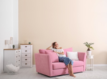 Photo of Happy young woman sitting under air conditioner at home