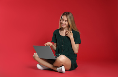Photo of Young woman with laptop on red background