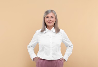 Portrait of beautiful senior woman on beige background