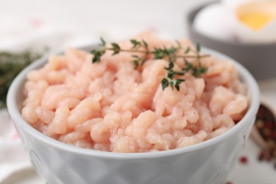 Photo of Fresh raw minced meat and thyme in bowl, closeup