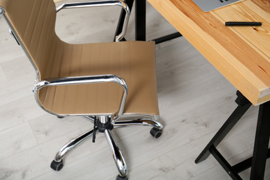 Photo of Comfortable workplace with office chair and wooden table